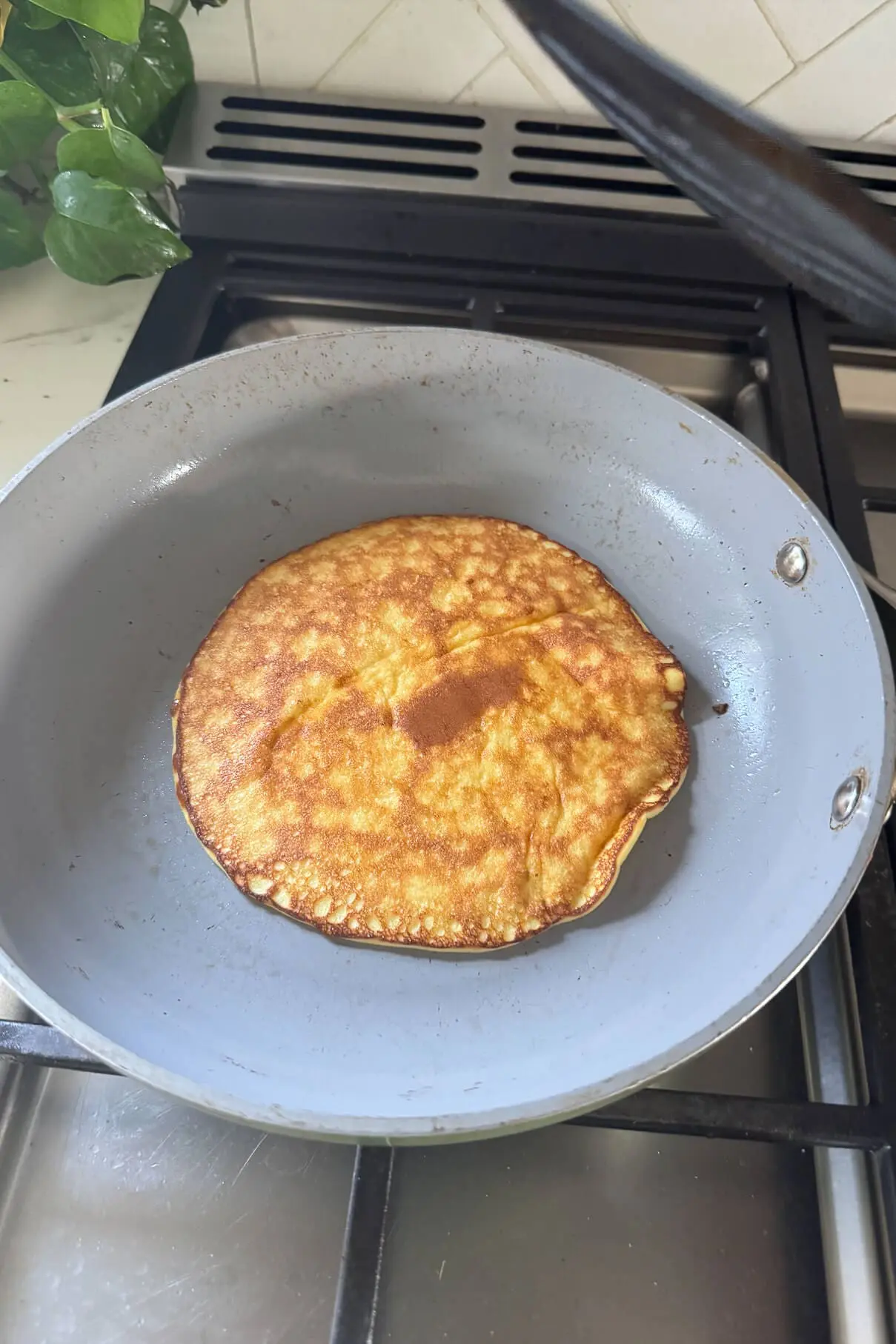 A fully cooked pancake with a rich golden-brown surface in a skillet, ready to be plated.